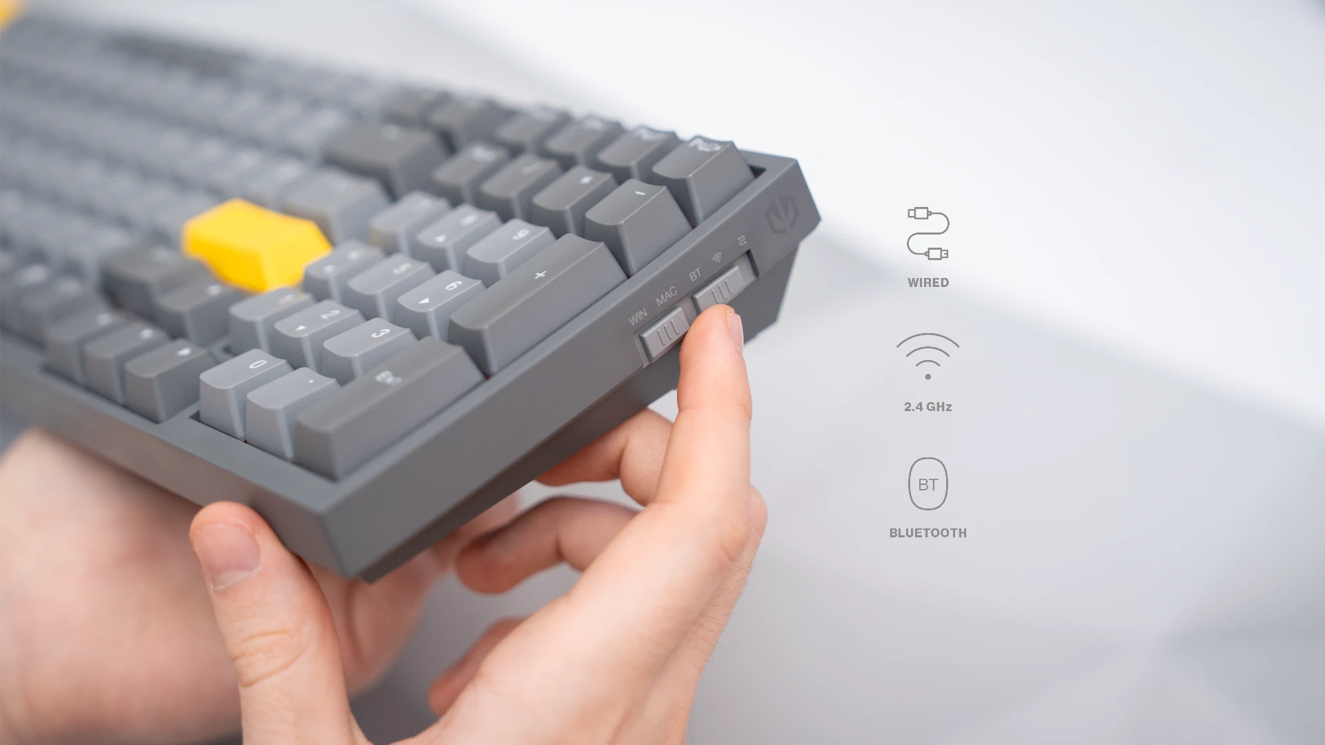 Ręka modela korzystająca z przełącznika Bluetooth / 2,4 GHz / USB-C, znajdującego się z boku klawiatury ENDORFY Celeris 1800 oraz ikony symbolizujące dostępne połączenia 