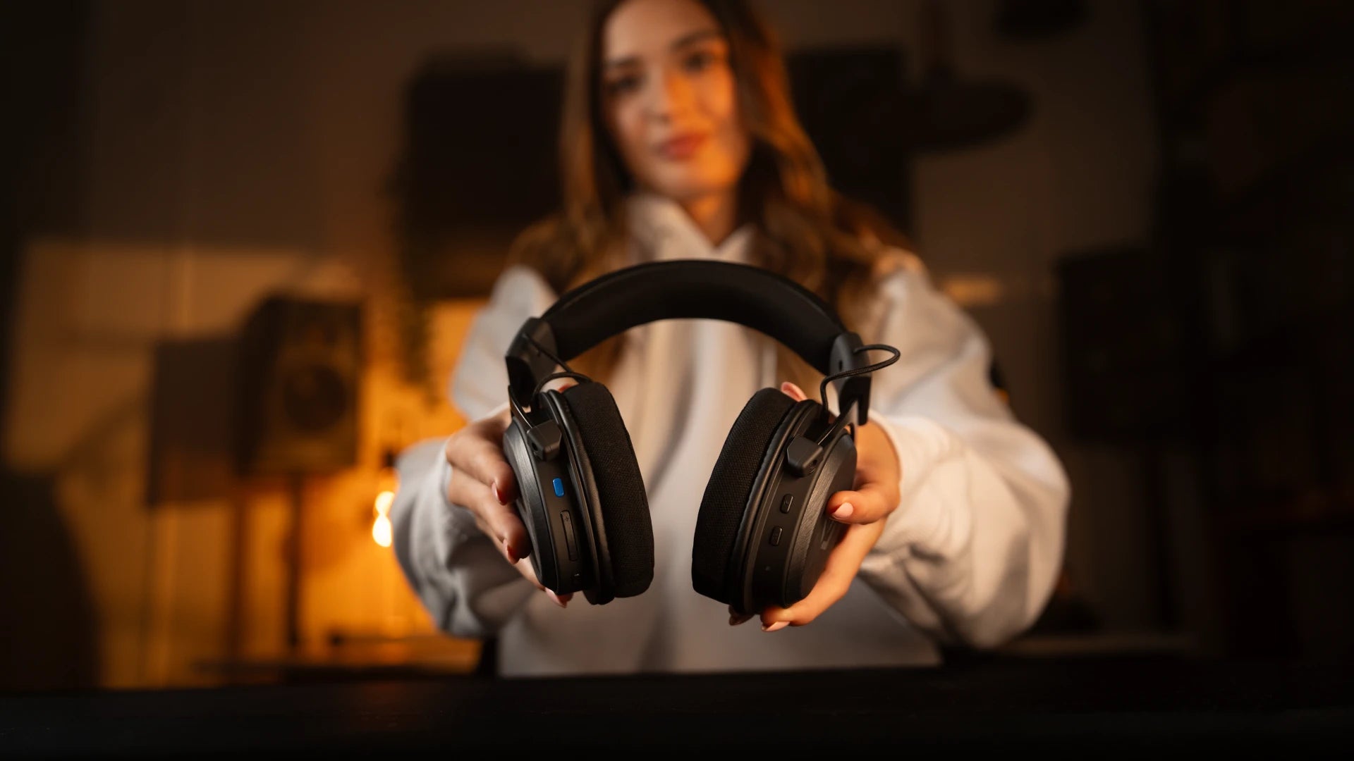 Close-up of a woman holding the ENDORFY Viro Infra Wireless headphones, highlighting the function buttons