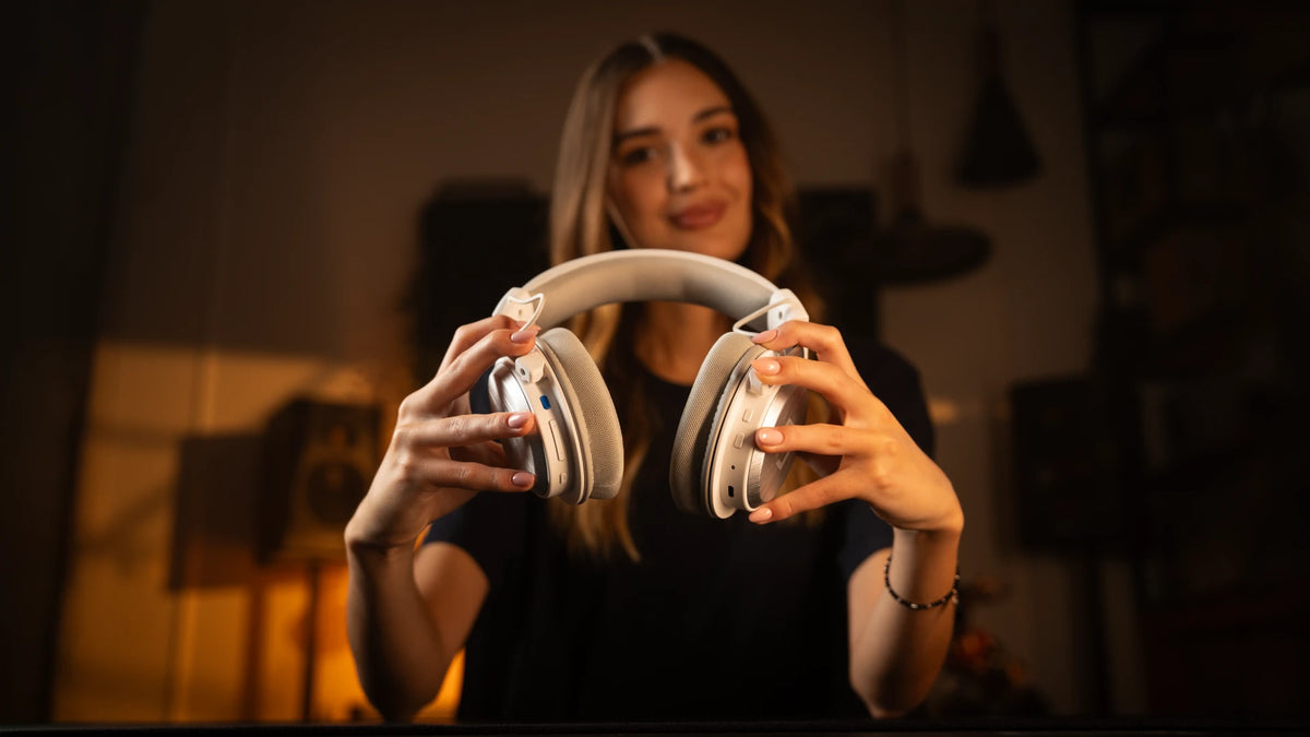 Close-up of a woman holding the ENDORFY Viro Infra Wireless Onyx White headphones, highlighting the on-ear function buttons
