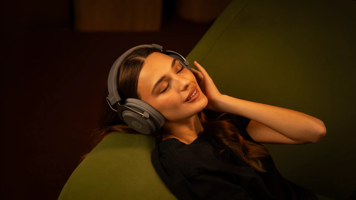 Woman resting on a sofa while wearing the ENDORFY Viro Infra Wireless Alt Gray headphones.