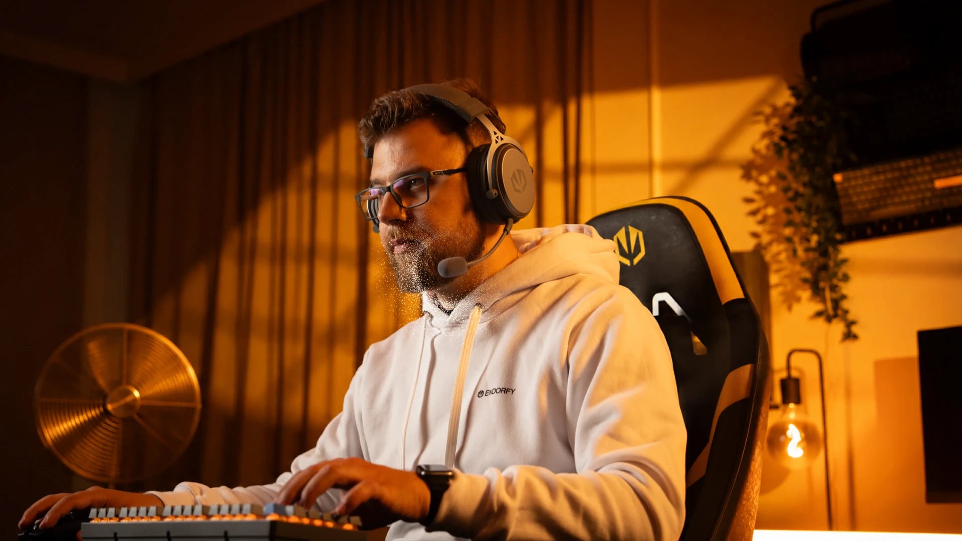 A model using ENDORFY Viro Wireless Alt Gray headphones with the microphone attached while using a computer