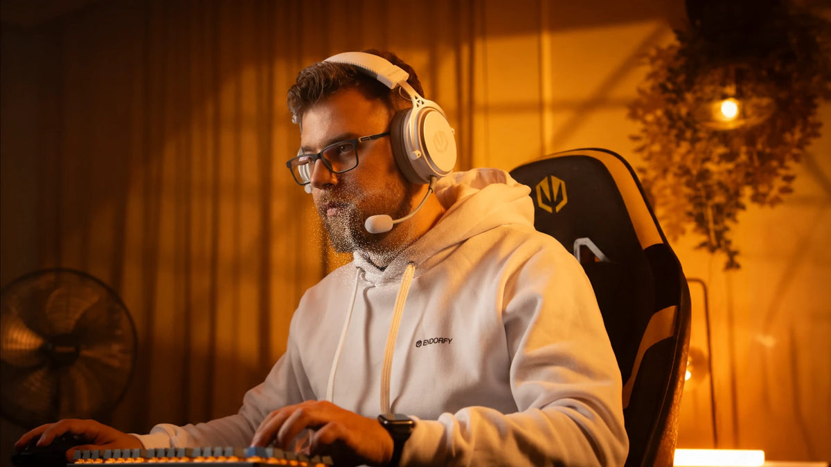A model using ENDORFY Viro Wireless Onyx White headphones with the microphone attached while using a computer
