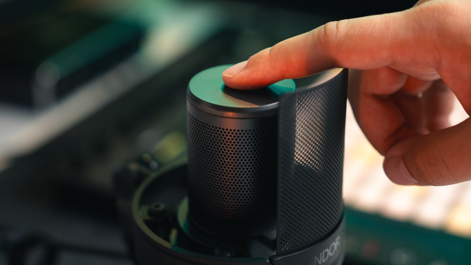 Close-up of a finger touching the mute button on the top panel of the Solum 2 Core microphone