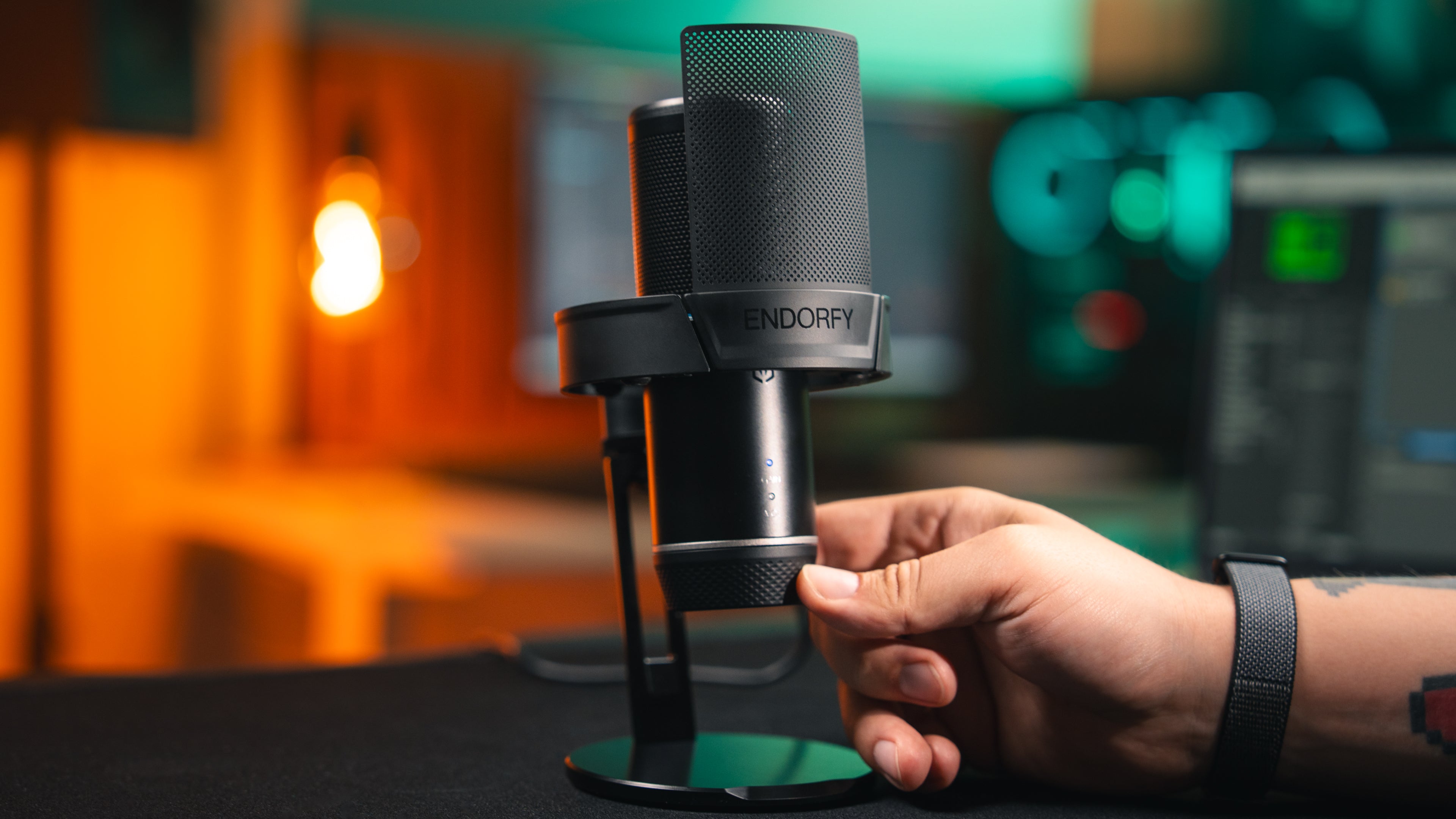 Close-up of a hand touching the sensitivity control knob on the base of the Solum 2 microphone