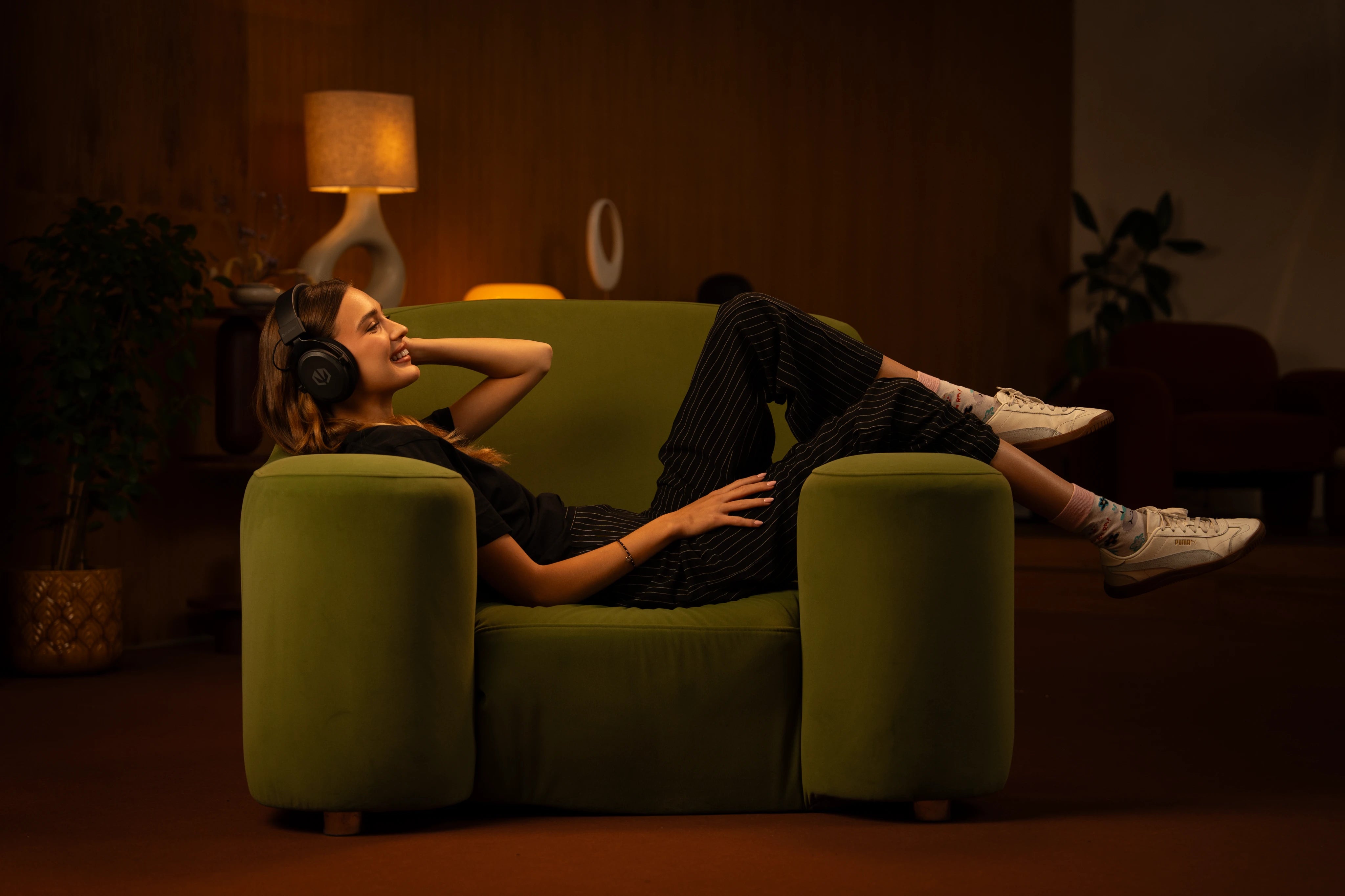 Woman relaxing comfortably in an armchair while listening to music through the ENDORFY Viro Infra Wireless wireless gaming headphones