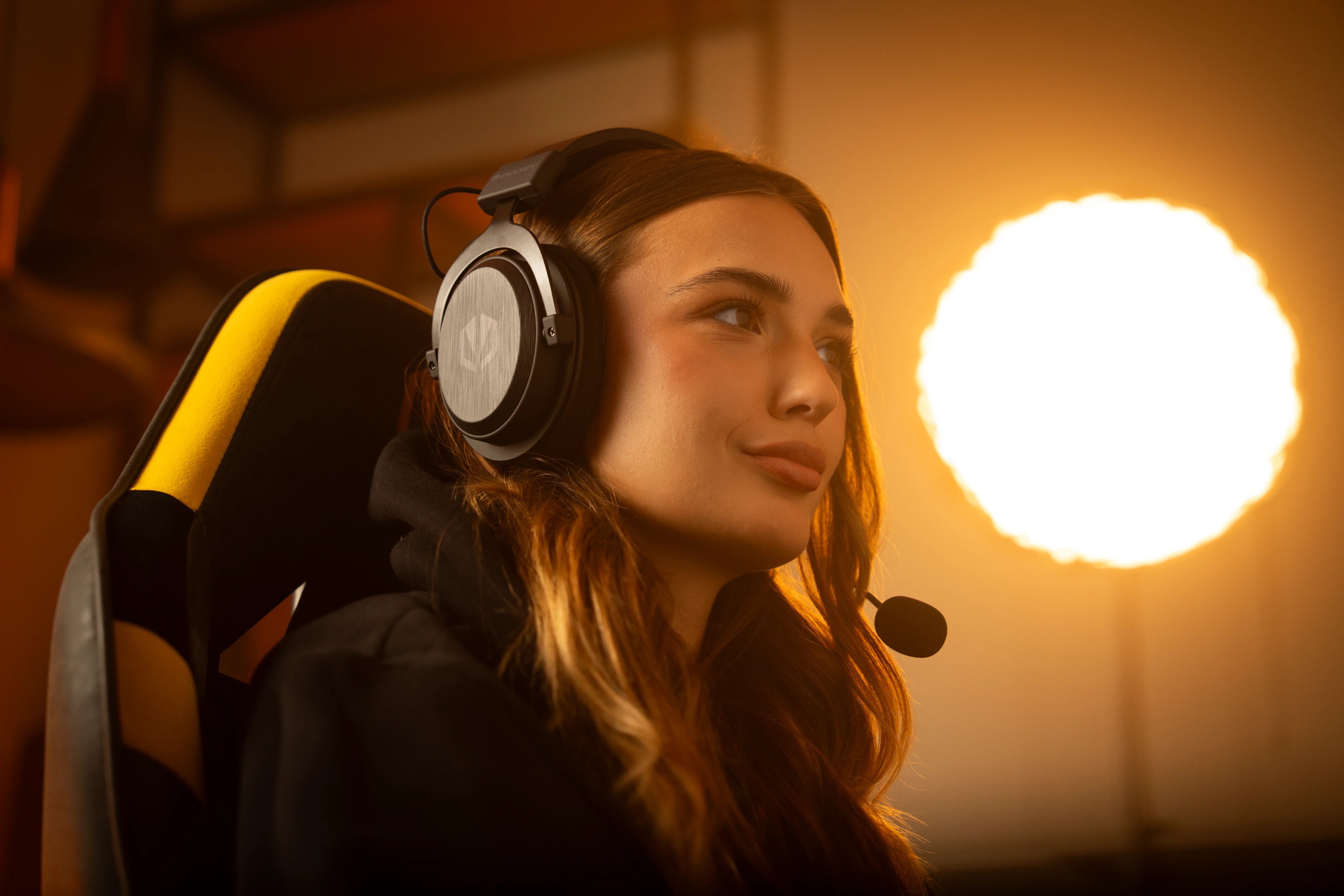 Woman sitting at her computer wearing the ENDORFY Viro Infra Wireless headphones with the microphone plugged-in, ready for gaming or voice chat
